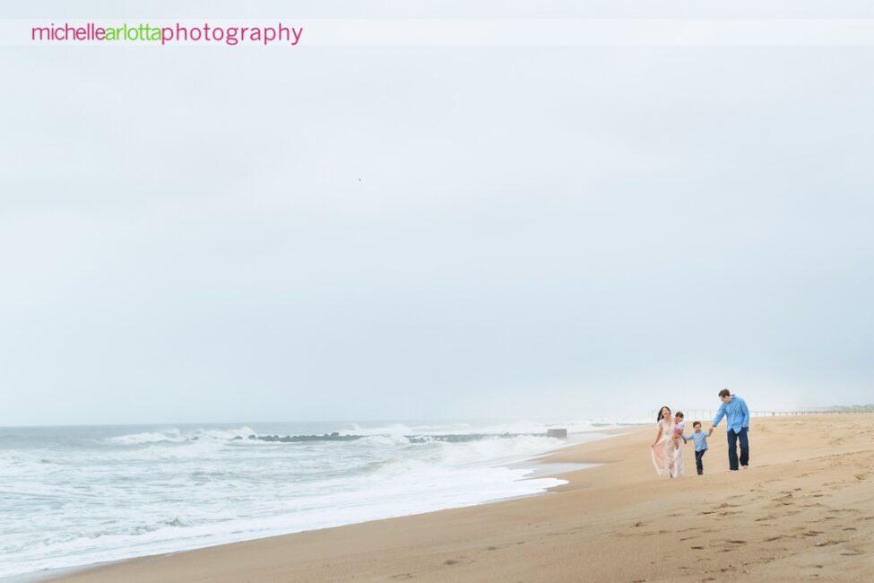 mother, father, son, daughter walk on beach during Asbury Park Beach NJ family portrait session