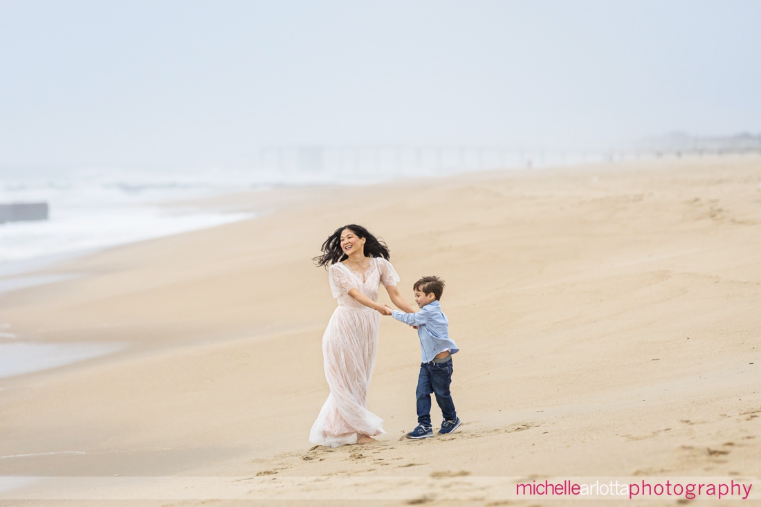 mother and son spin around and play on NJ beach during family portrait session