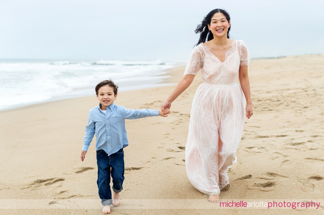 mother and son holding hands and walking on the beach in Asbury Park, New Jersey