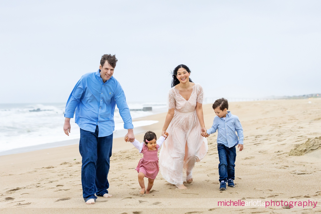 mother, father, son, daughter walk on beach during Asbury Park Beach NJ family portrait session