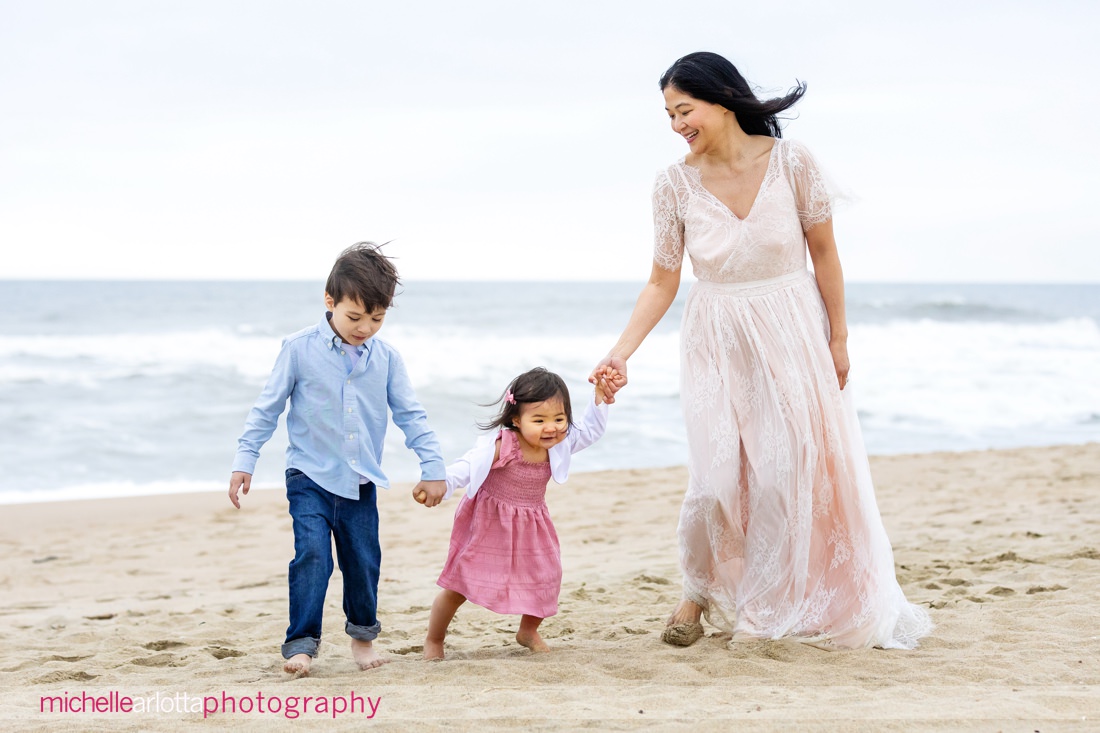 mother, son and daughter hold hands and walk on the beach in New Jersey