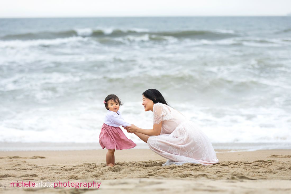 mother squats down on the beach to look daughter in the face in NJ