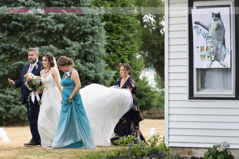 South Jersey Backyard wedding ceremony bride walks out of house with parents with cat bathroom sign on house