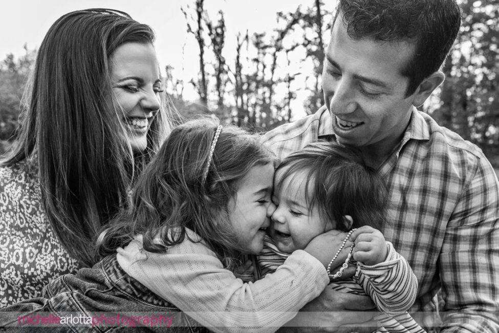 black and white family photo of big sister rubbing noses with little sister New Jersey