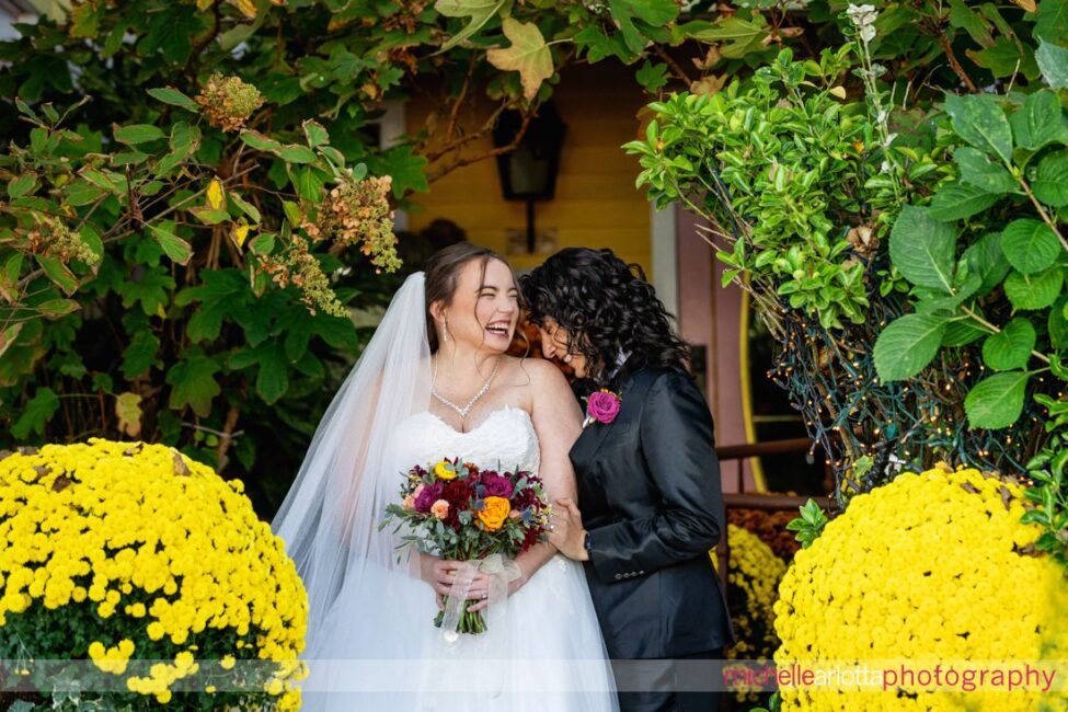 bride in white wedding gown with bride in black suit and bowtie in front of The Gables Inn for their Late Fall LBI NJ wedding