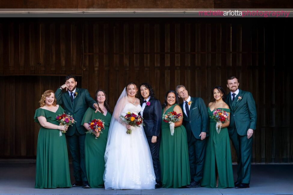 bridal party in green dresses white bride in black suit with black bow tie and bride in white wedding gown at late fall gables inn lbi nj wedding