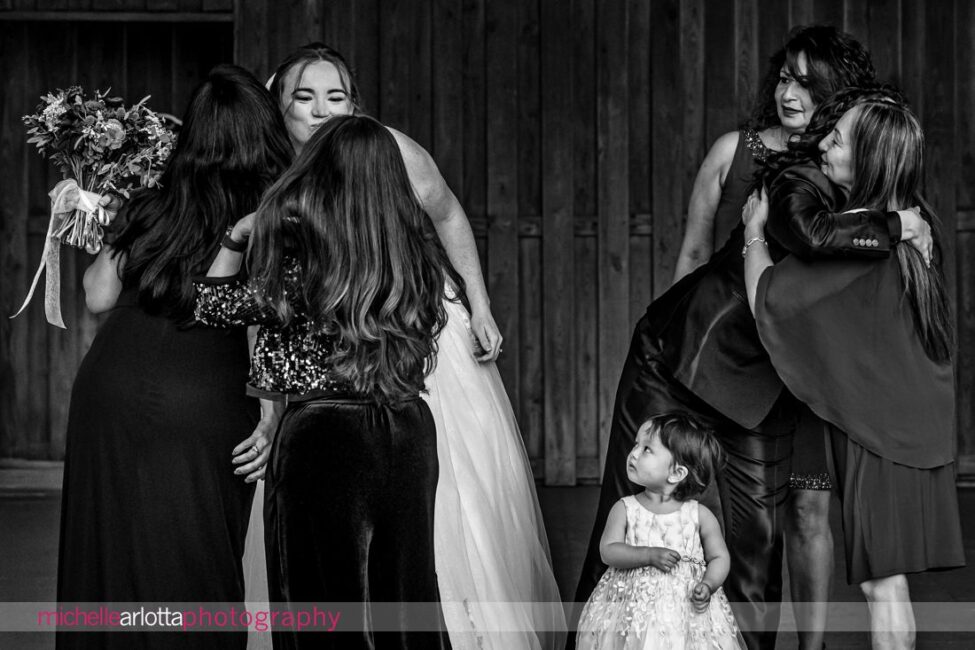 brides hug aunts at little one watches on during LBI family portraits for late fall wedding