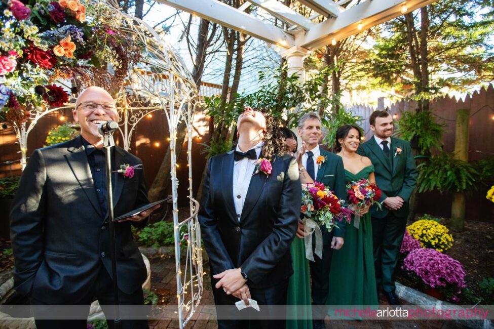 bride in black suit and black bow tie gets emotional as bride in white wedding dress starts to walk down the aisle at late fall gables lbi nj wedding