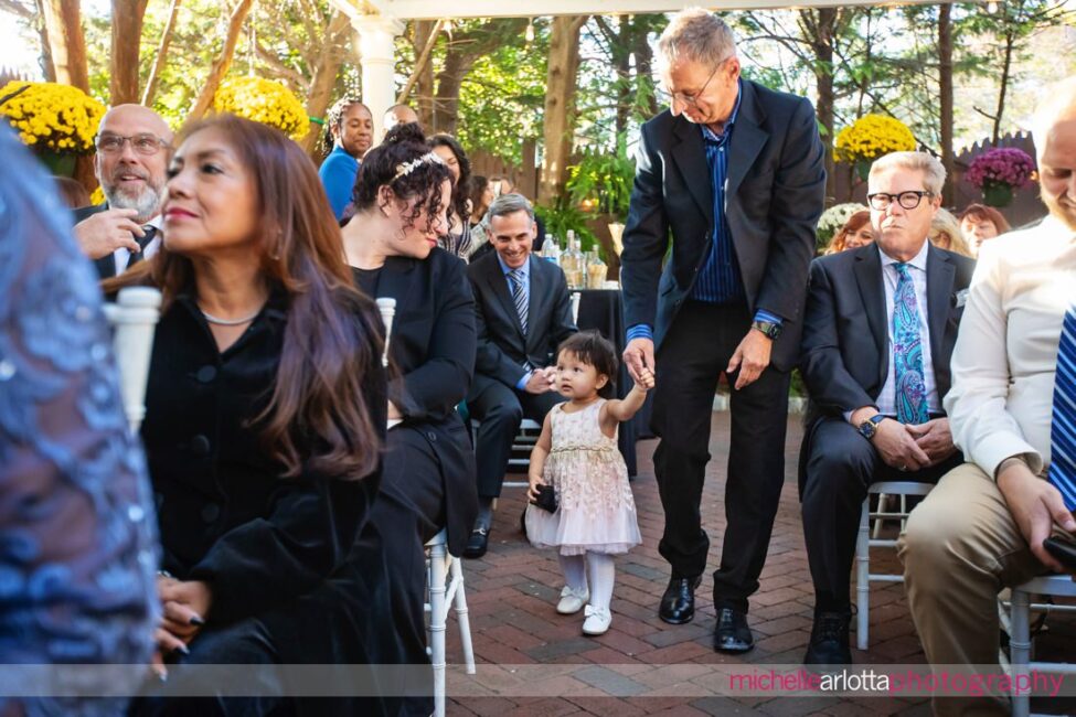 flower girls walks down the aisle in the outdoor garden ceremony at gables LBI wedding