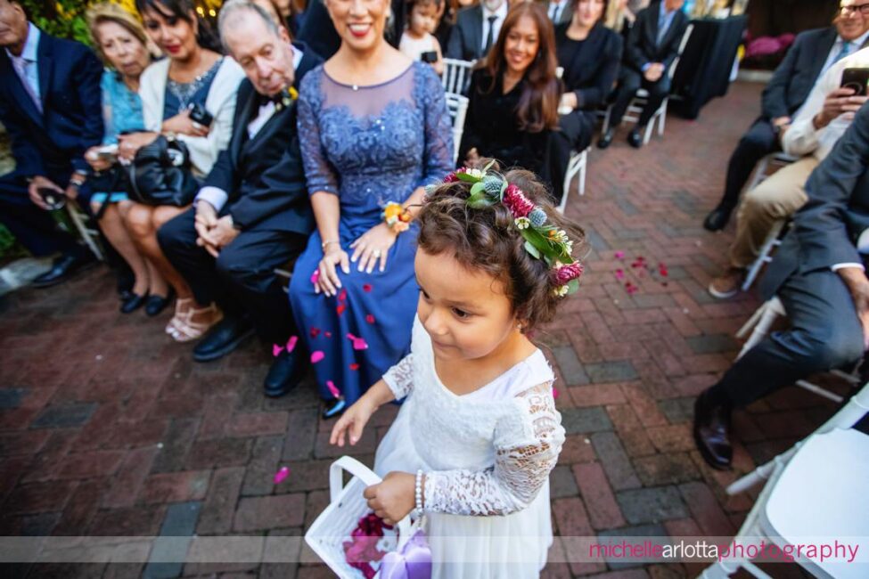 flower girls walks down the aisle in the outdoor garden ceremony at gables LBI wedding