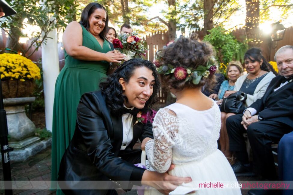 flower girls walks down the aisle in the outdoor garden ceremony at gables LBI NJ wedding and is greeted by bride at the altar