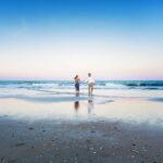 couple walks hand in hand beach haven lbi beach for engagement photos