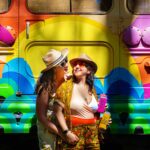 same sex couple in front of colorful bus during engagement session