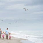 family walking hand in hand on LBI NJ beach with seagulls