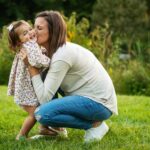 mom squats down to kiss toddler daughter during nj candid family photos