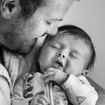 black and white image of father with newborn who is smiling