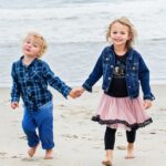 brother and sister hold hands on new jersey beach during lifestyle family photo session