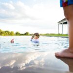 dad tells son to behave in pool while other son looks on during nj lifestyle photography session