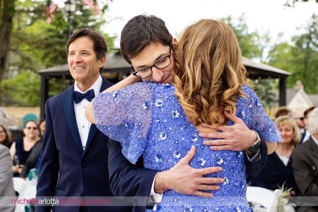 bride hugs mother at altar during lakeside Lake Mohawk Country Club nj wedding ceremony