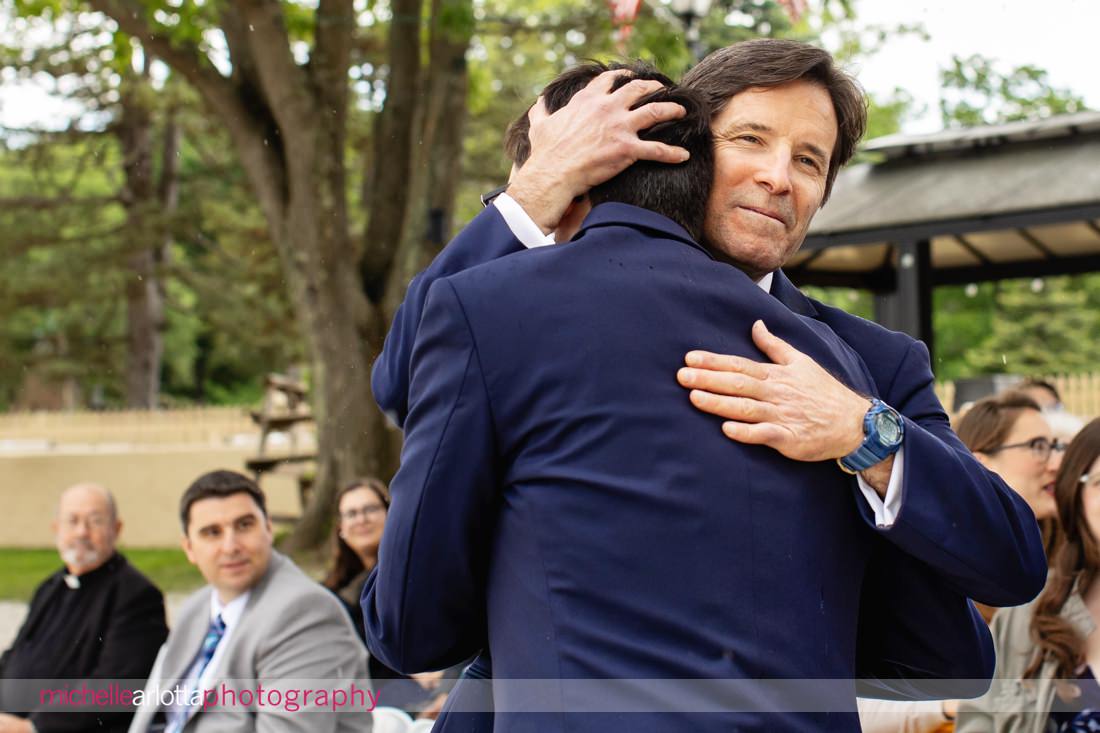 groom hugs father at altar at akeside Lake Mohawk Country Club nj wedding ceremony