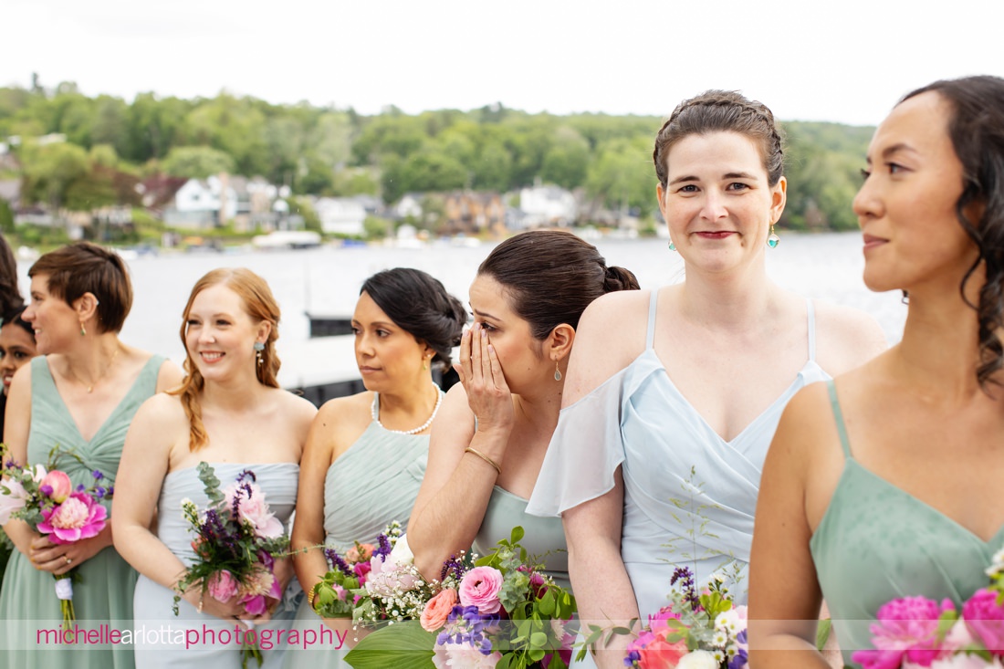 bridesmaid cries at bride walks down the aisle during lake mohawk country club spring lakeside wedding ceremony