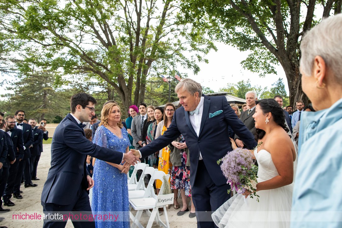 bride's father reaches out to shake hands with groom at the altar of NJ lakeside wedding