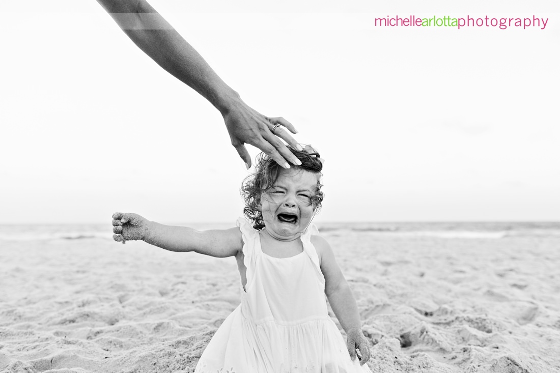 toddler crying on the beach in LBI as mother reaches out and touches her head