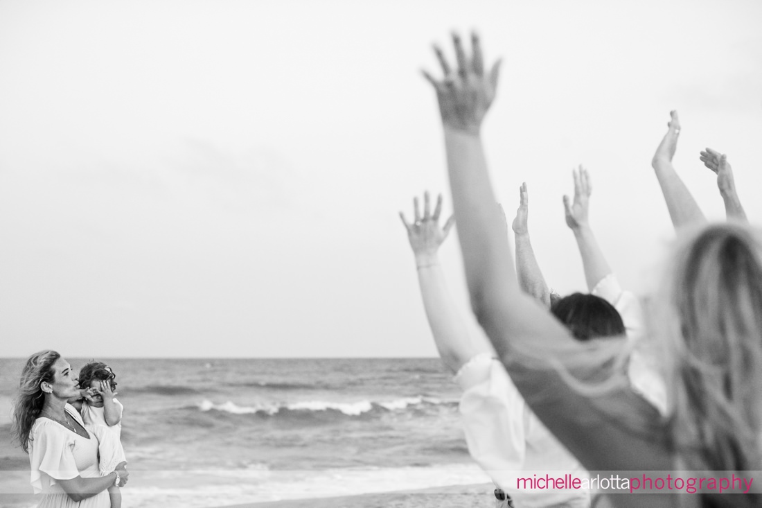 family trying to make toddler smile for a picture on the beach