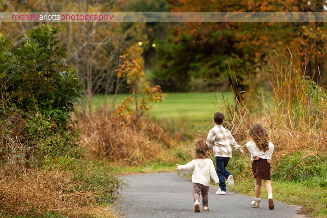 three little kids running away from the camera during fall NJ family photo session